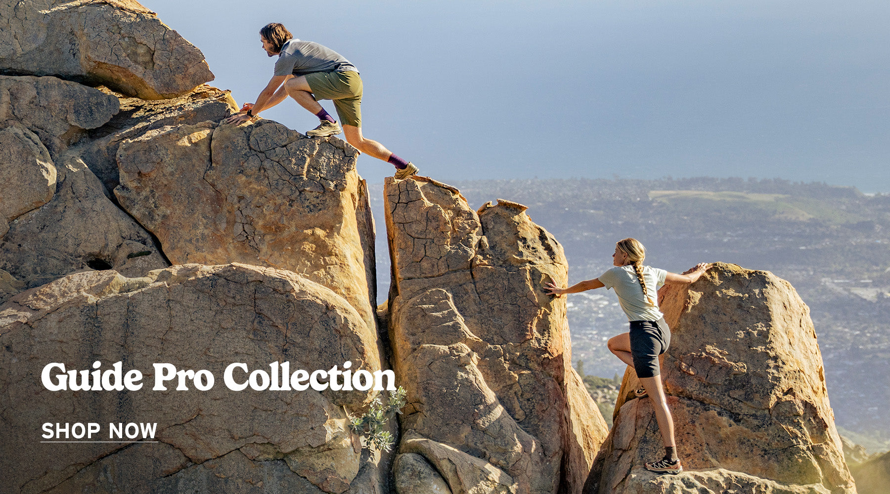 Aman and a woman climbing along a rocky mountain ridge wearing technical t-shirts and shorts