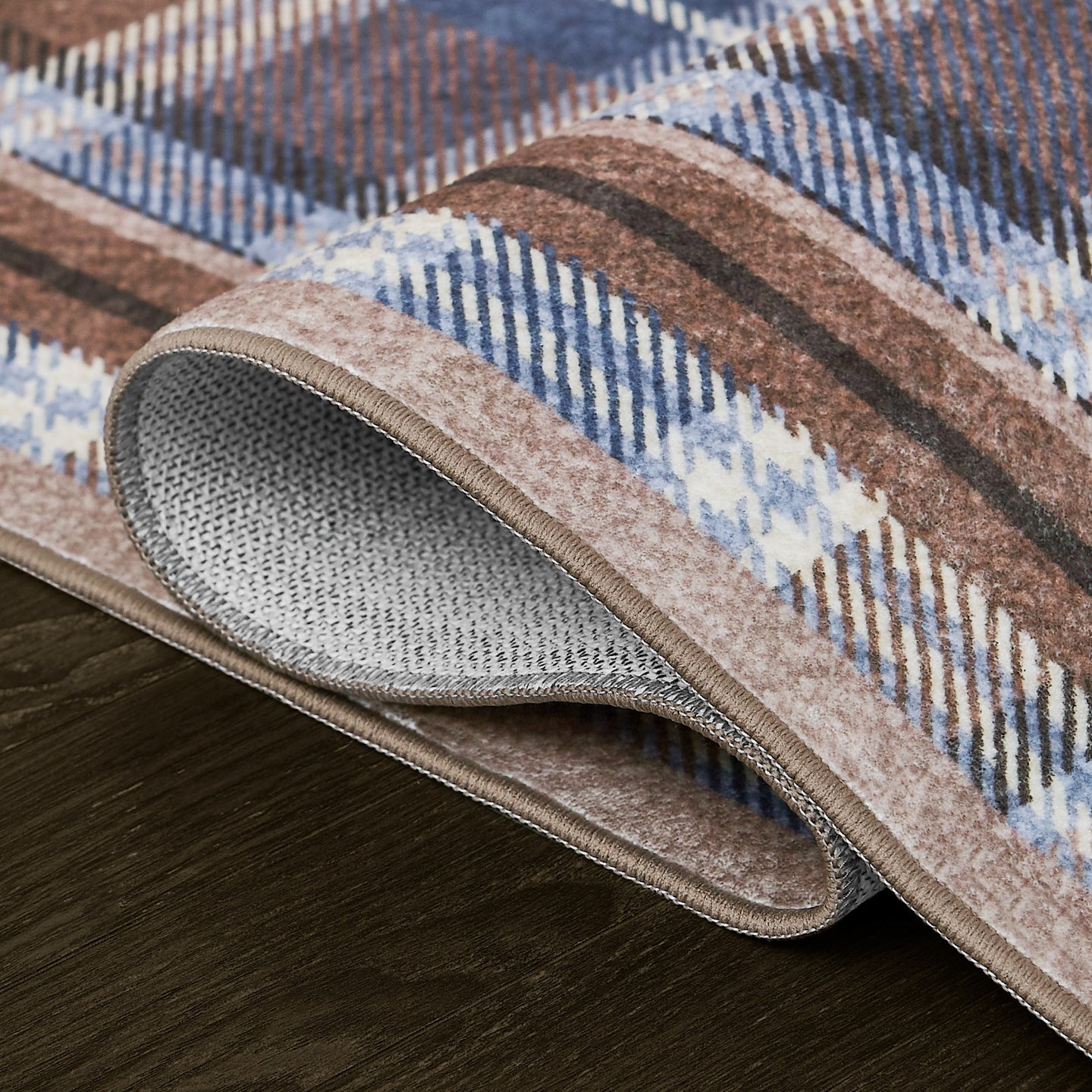 Patterned rug with brown, blue, and beige colors on a wooden floor.