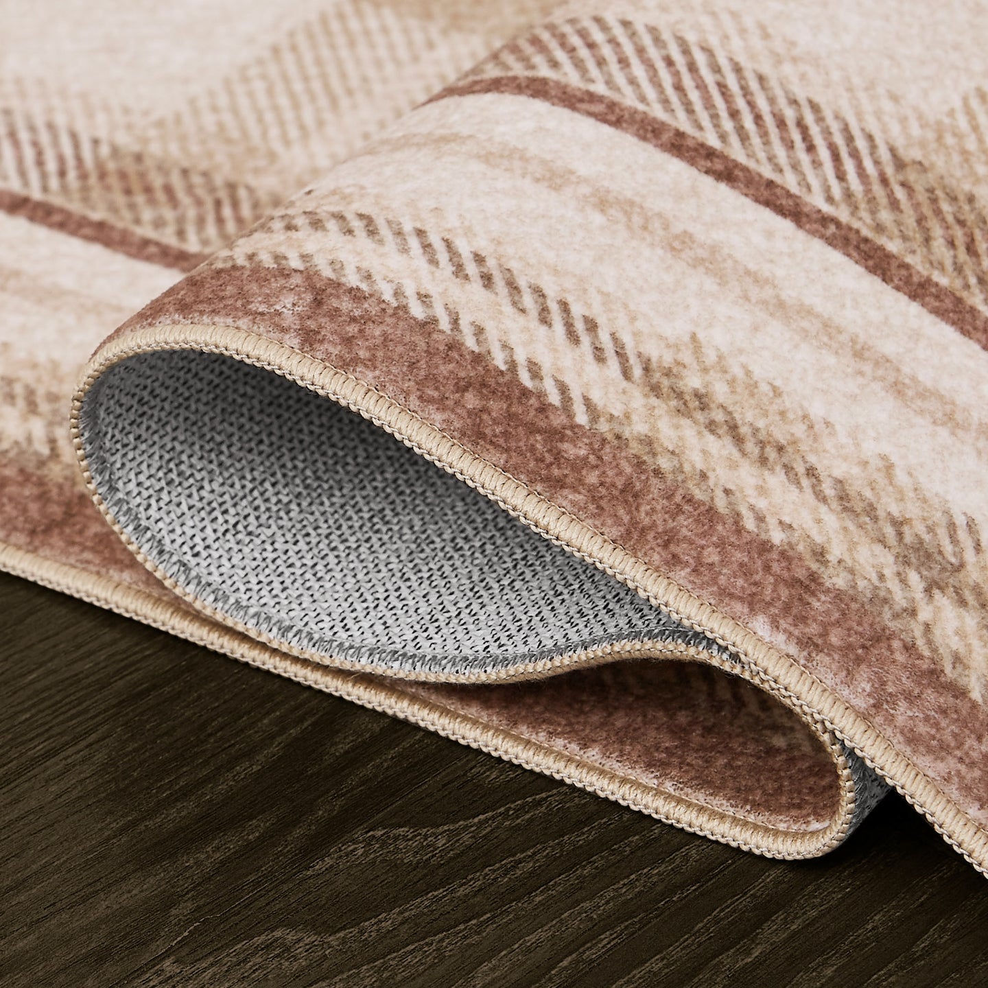 Close-up of a plaid-patterned rug with a textured surface on a wooden floor.