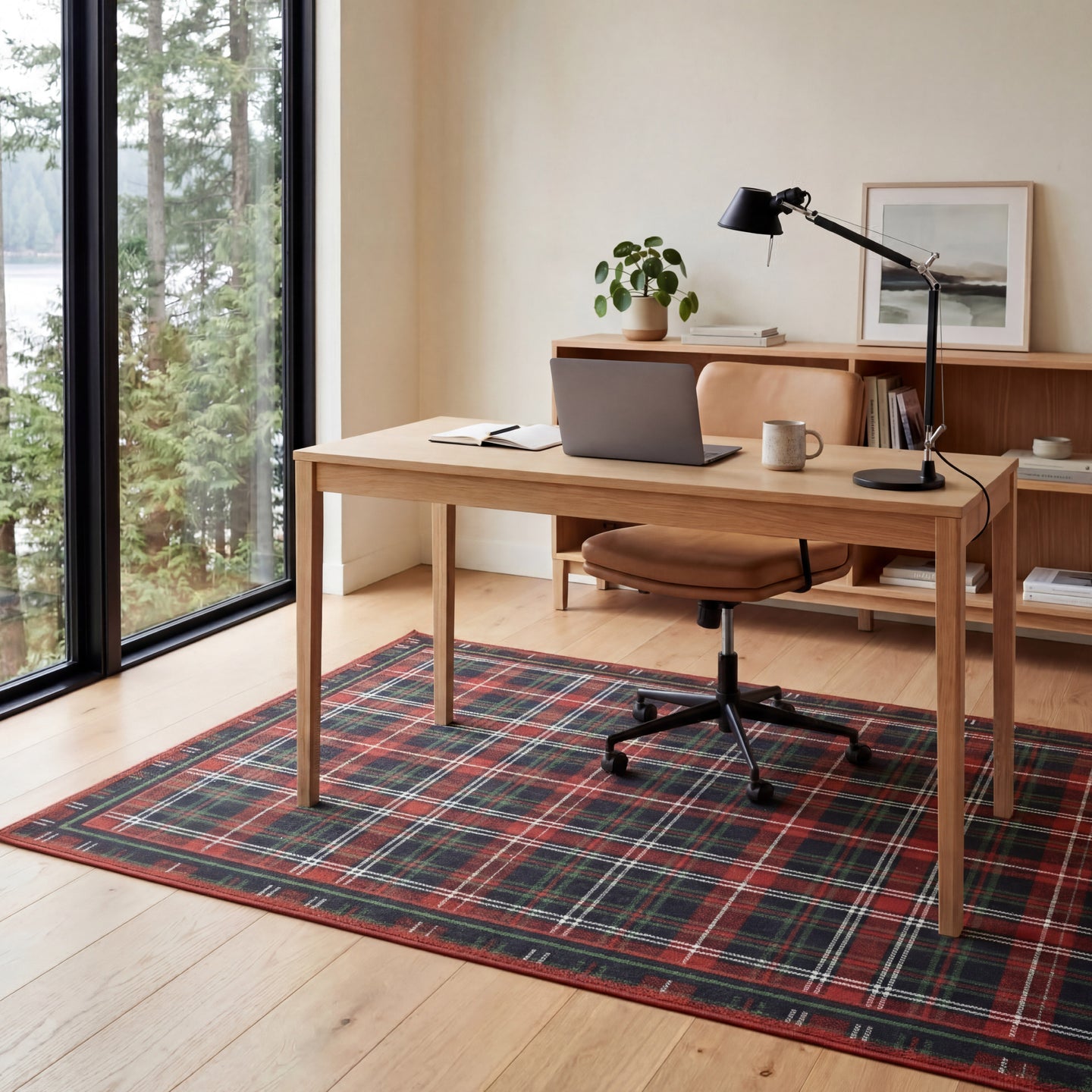 Home office with wooden desk, chair, laptop, and decor items on a plaid rug.