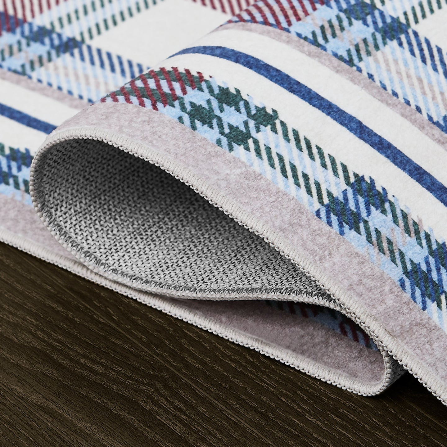 Close-up of a textured rug with plaid pattern on a wooden floor.